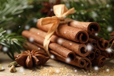 Different spices and fir tree branches on wooden table, closeup. Cinnamon, anise, cardamom