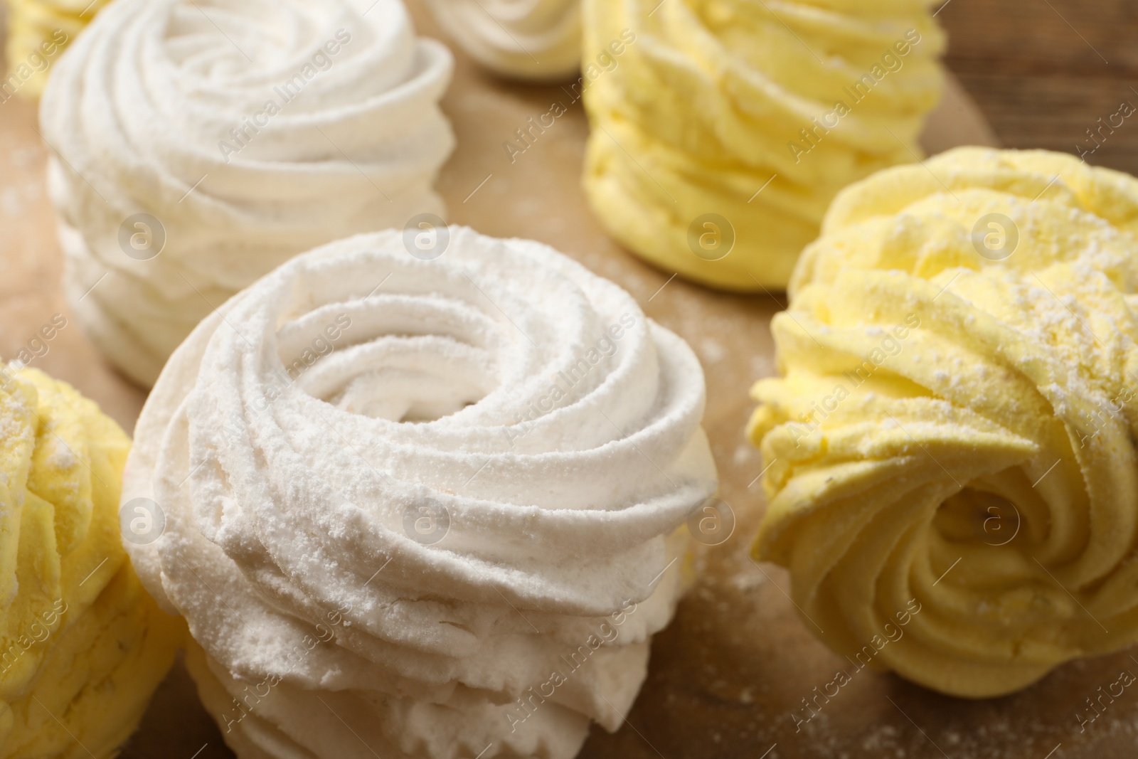 Photo of Many delicious yellow and white marshmallows on parchment paper, closeup