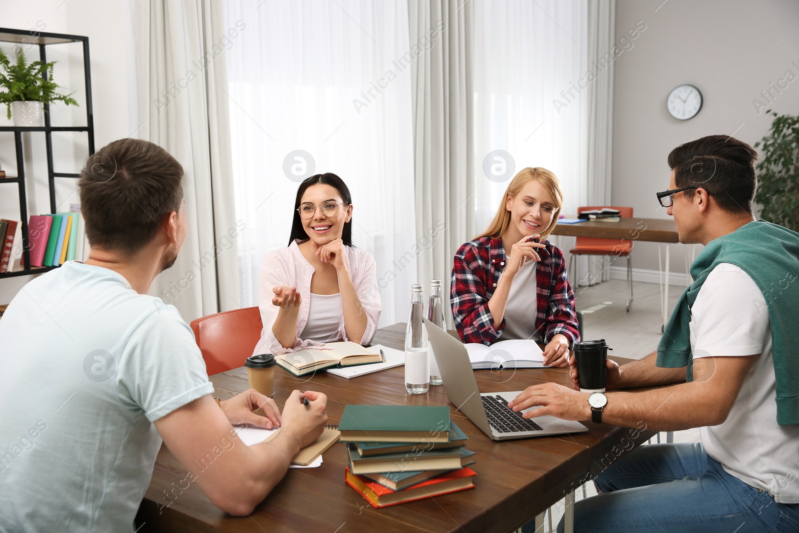 Photo of Young people discussing group project at table in library