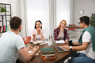 Photo of Young people discussing group project at table in library