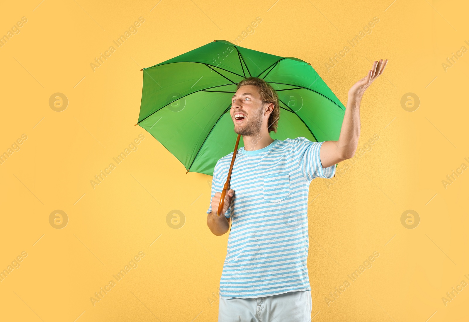 Photo of Man with green umbrella on color background