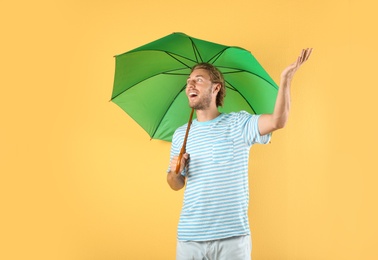 Photo of Man with green umbrella on color background