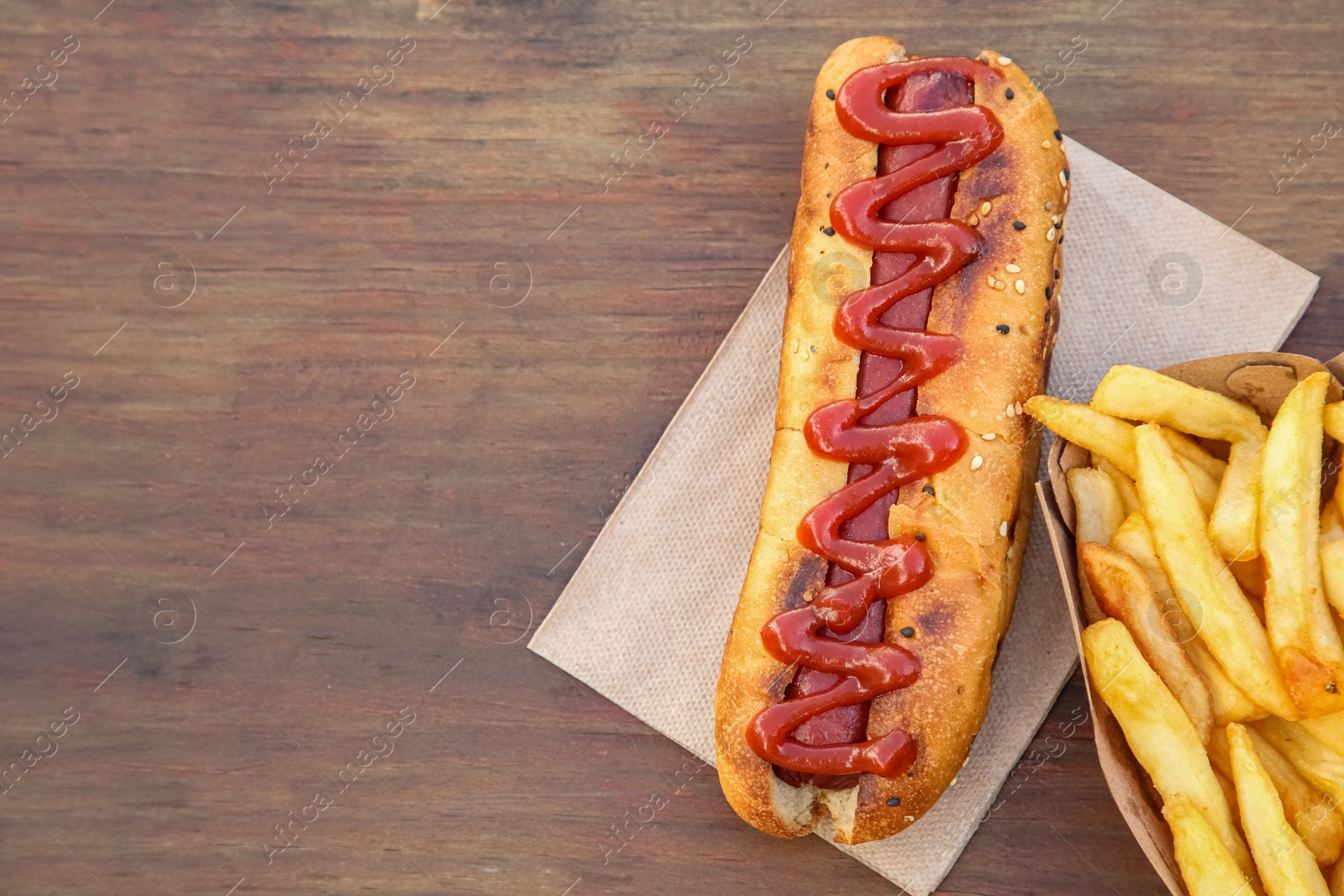 Photo of Fresh tasty hot dog and french fries on wooden table, flat lay. Space for text