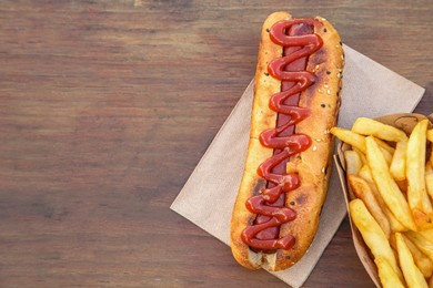 Photo of Fresh tasty hot dog and french fries on wooden table, flat lay. Space for text