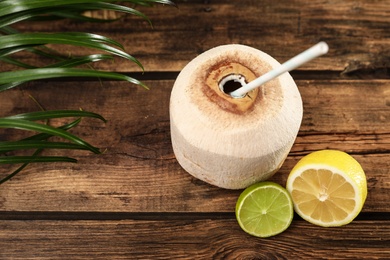 Photo of Open fresh coconut and citrus fruits on wooden table, above view