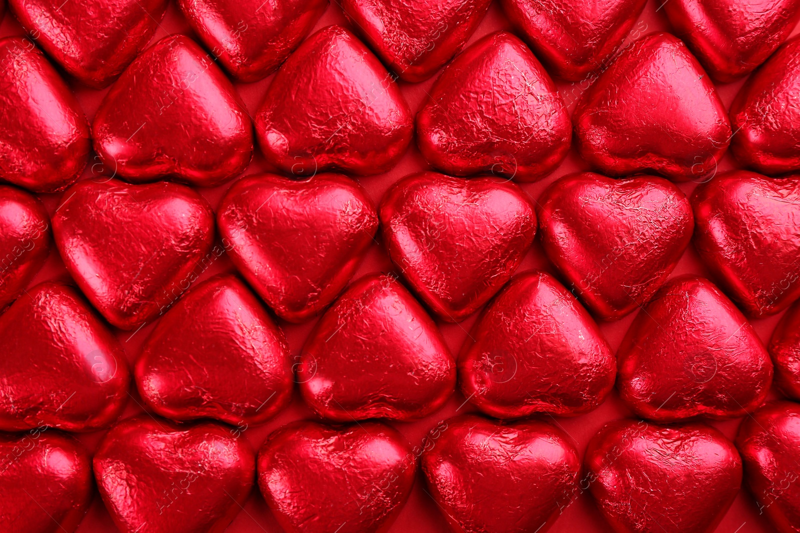 Photo of Heart shaped chocolate candies on red background, flat lay