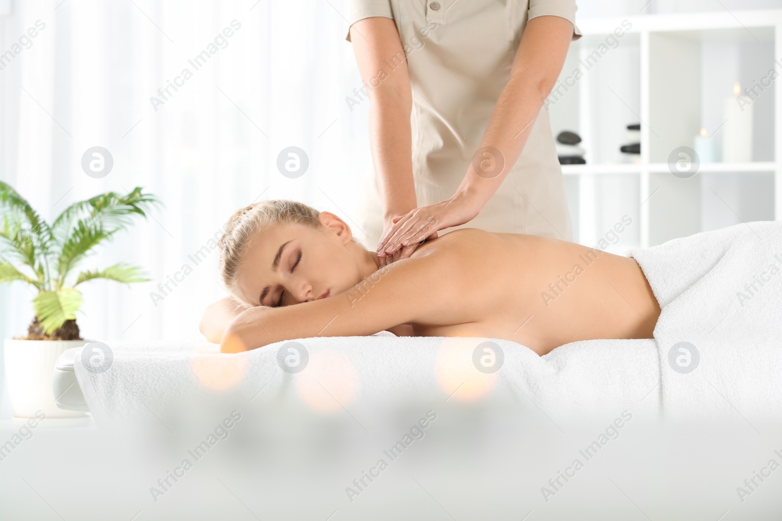 Photo of Relaxed woman receiving back massage in wellness center