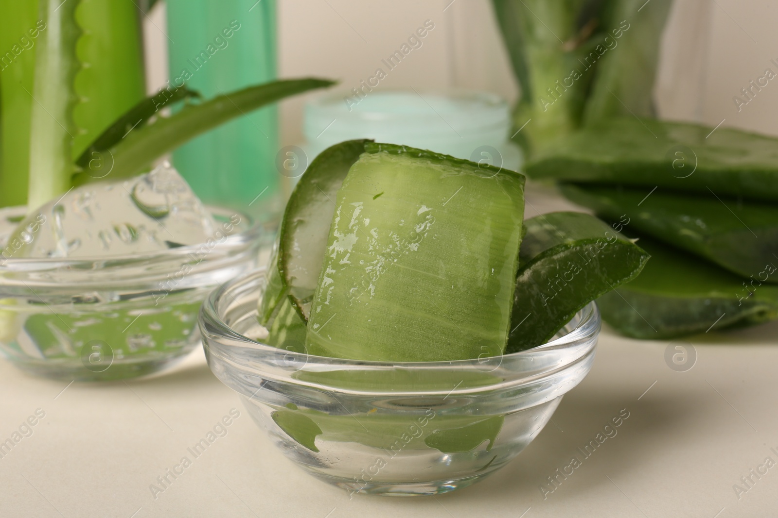 Photo of Bowl with natural gel and cut aloe on beige background, closeup