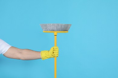 Photo of Man with yellow broom on light blue background, closeup