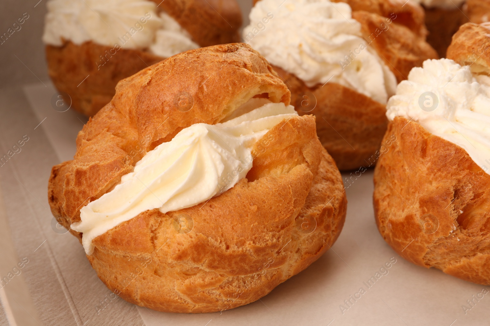 Photo of Delicious profiteroles with cream filling on table, closeup