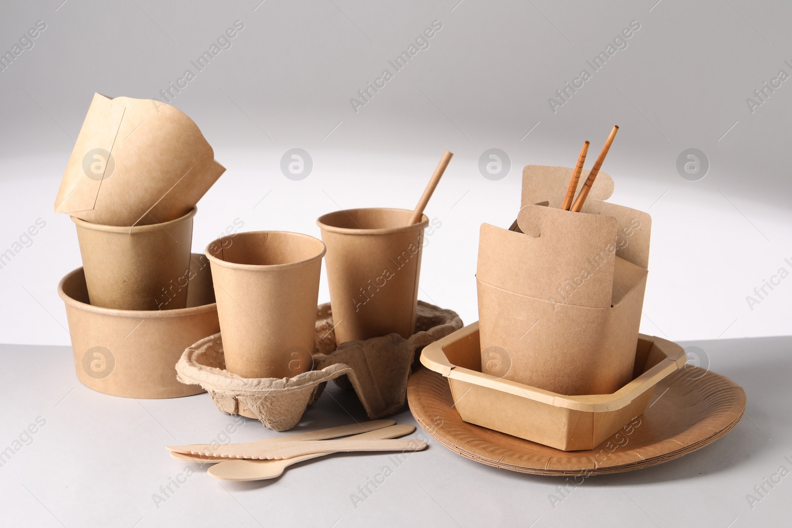 Photo of Eco friendly food packaging. Paper containers and tableware on light background