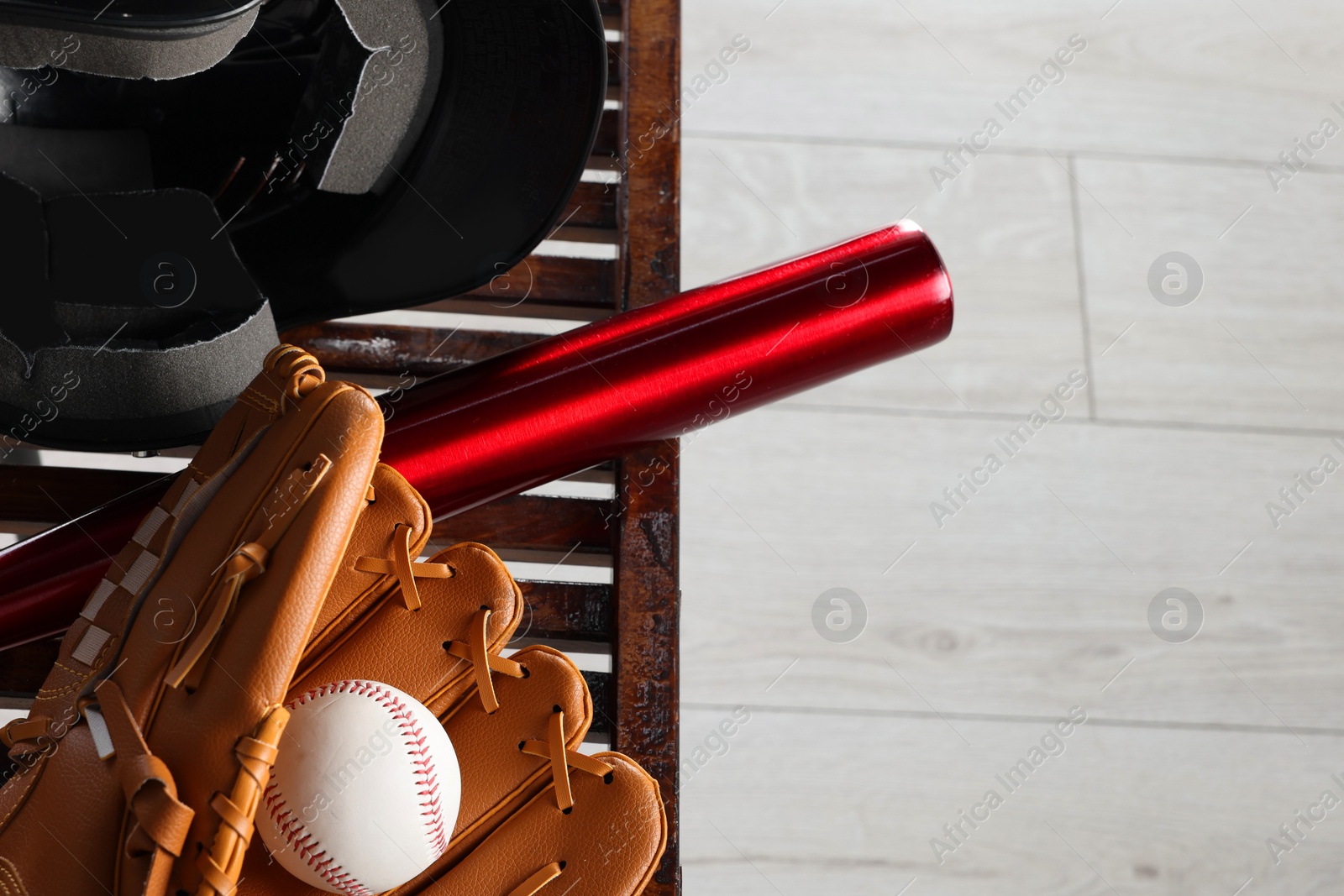 Photo of Baseball bat, batting helmet, leather glove and ball on bench indoors, closeup. Space for text