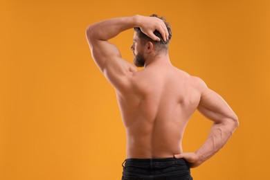 Muscular man on orange background, back view. Sexy body