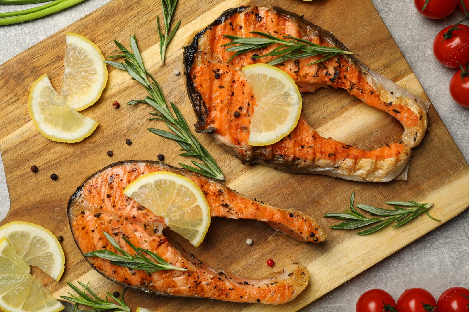 Photo of Tasty grilled salmon steaks and different ingredients on light grey table, flat lay