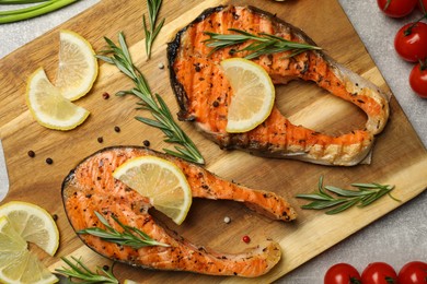 Tasty grilled salmon steaks and different ingredients on light grey table, flat lay