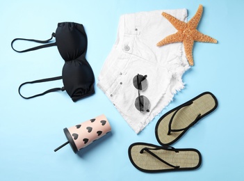 Photo of Flat lay composition with stylish beach accessories on light blue background