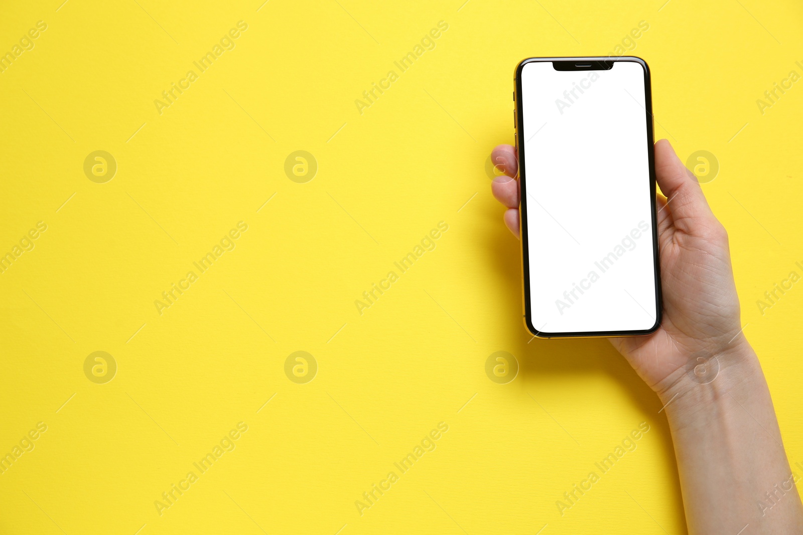 Photo of Woman with smartphone on yellow background, top view. Space for text