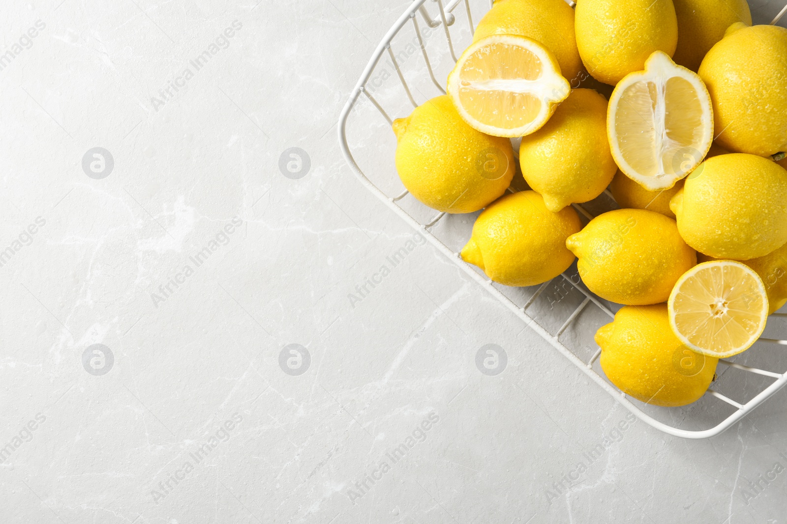 Photo of Wire basket with lemons on gray table, top view