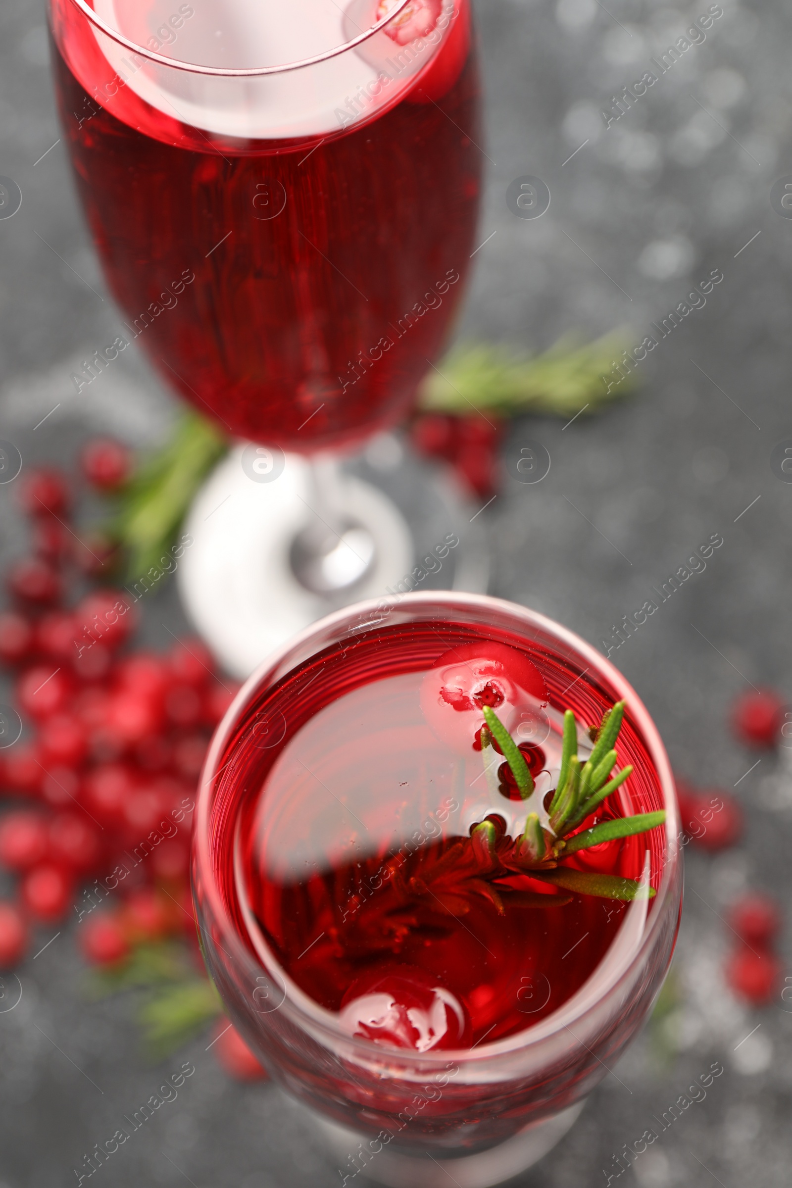 Photo of Tasty cranberry cocktail with rosemary in glasses on gray table, above view