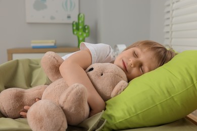 Photo of Little boy snoring while sleeping with teddy bear in bed at home