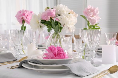 Stylish table setting with beautiful peonies in dining room