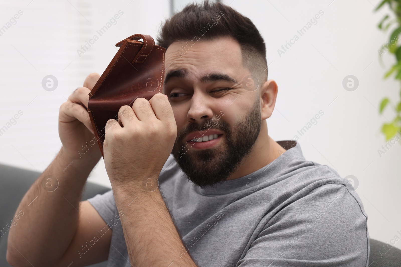 Photo of Upset man with empty wallet at home