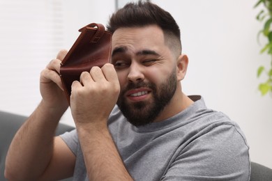 Upset man with empty wallet at home