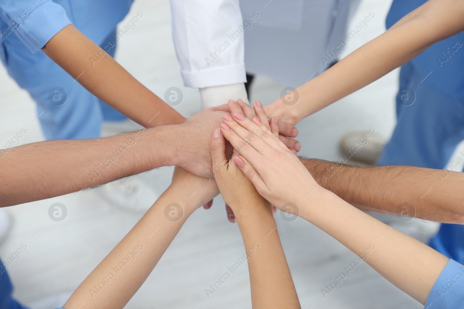 Photo of Doctor and interns stacking hands together indoors, closeup