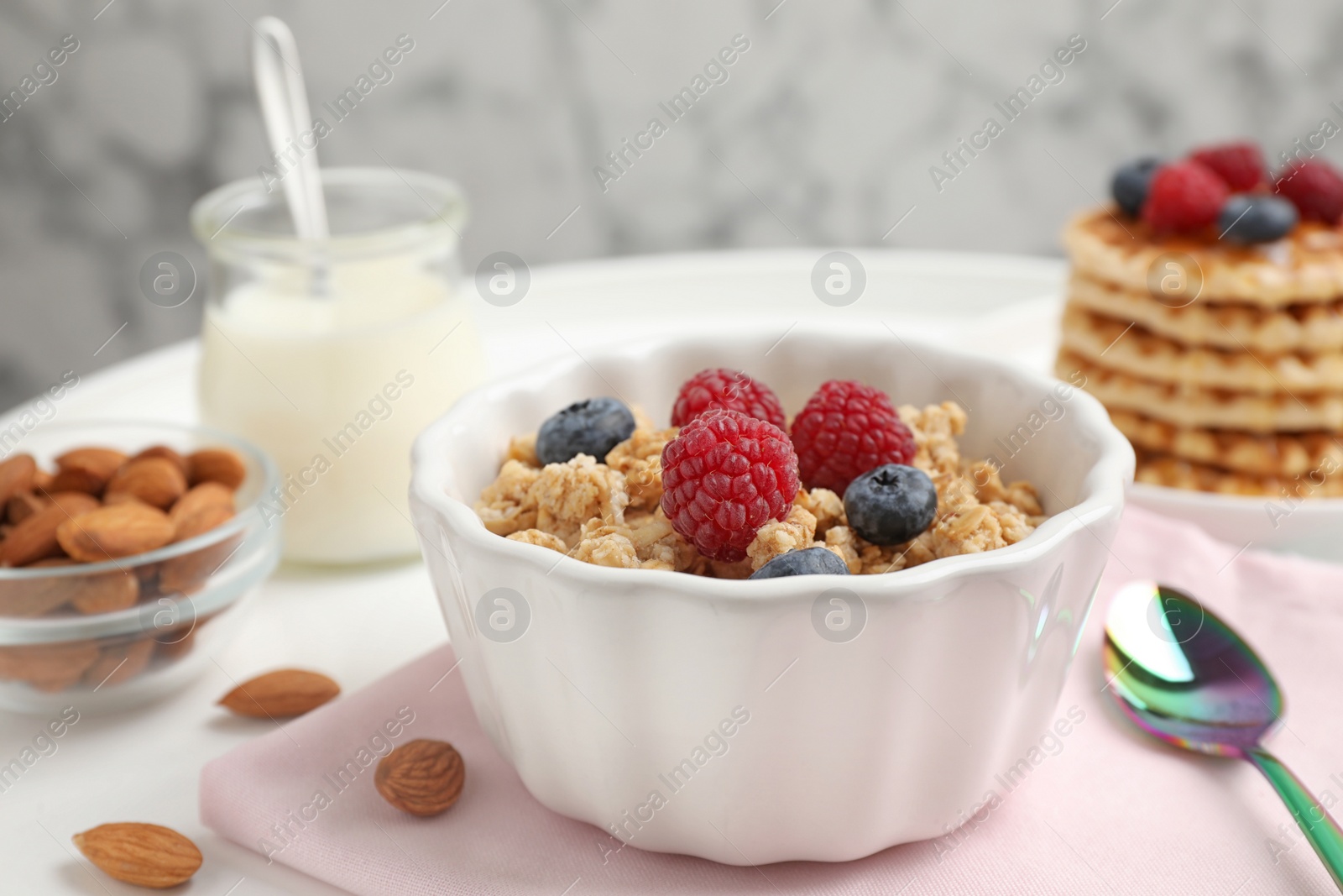 Photo of Healthy breakfast with granola and berries served on white table