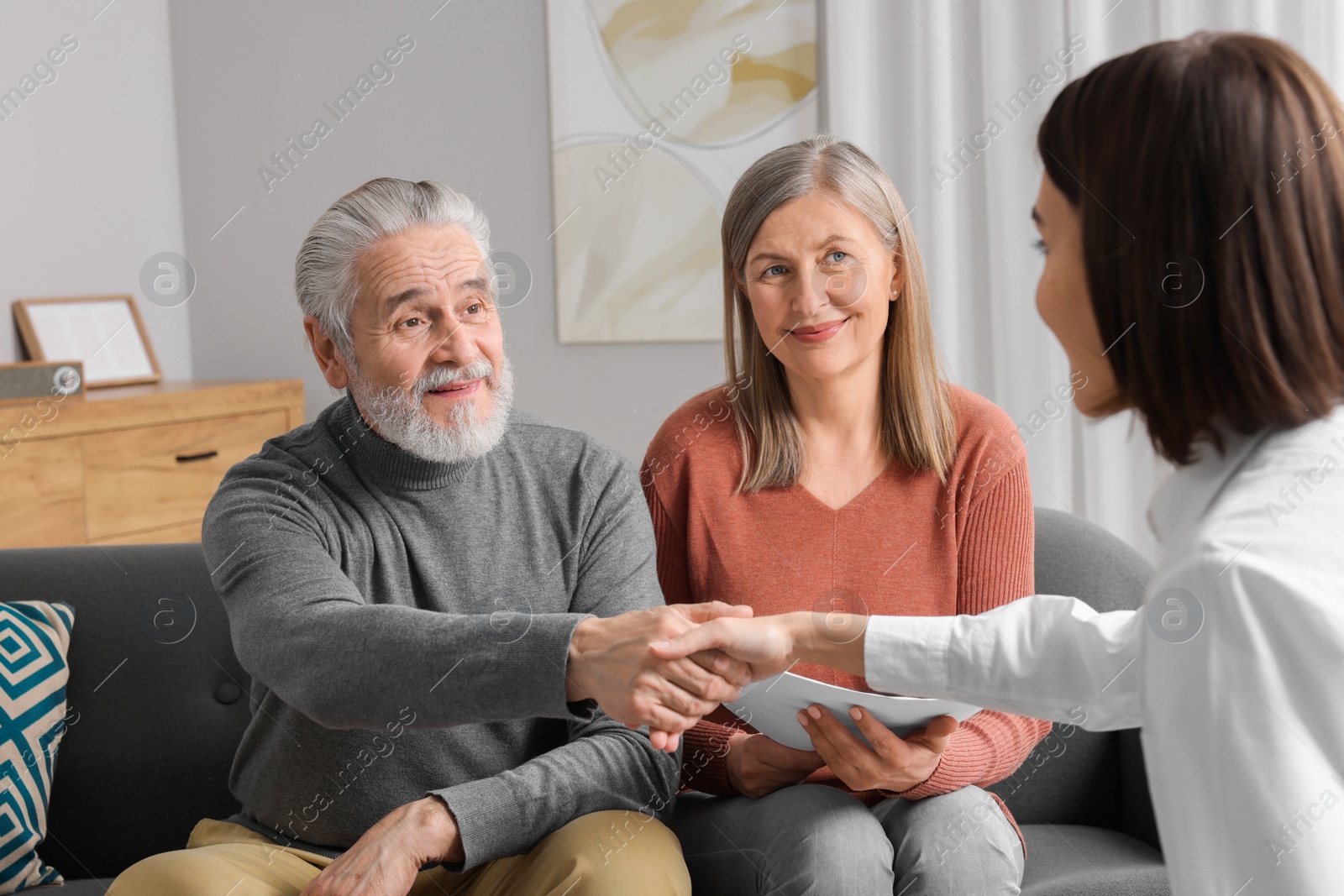 Photo of Insurance agent consulting elderly couple about pension plan in room