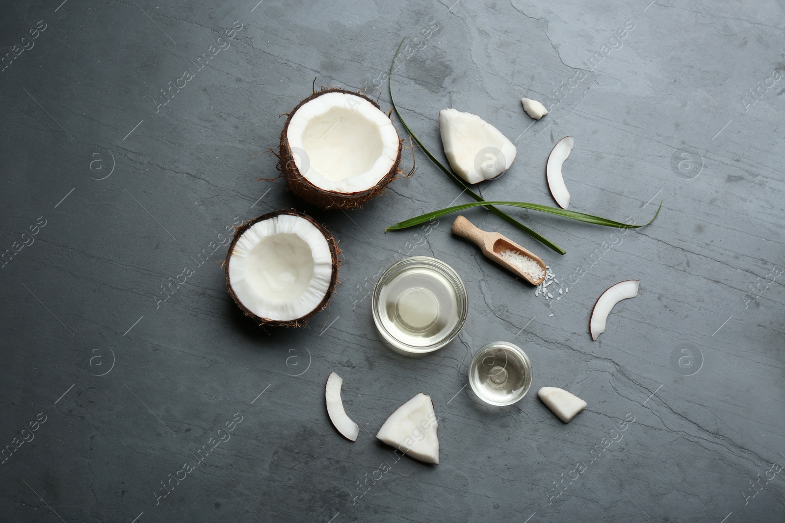 Photo of Bowls of natural organic oil and coconuts on grey stone background, flat lay