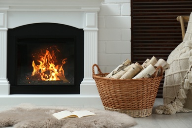 Photo of Firewood in wicker basket near fireplace indoors