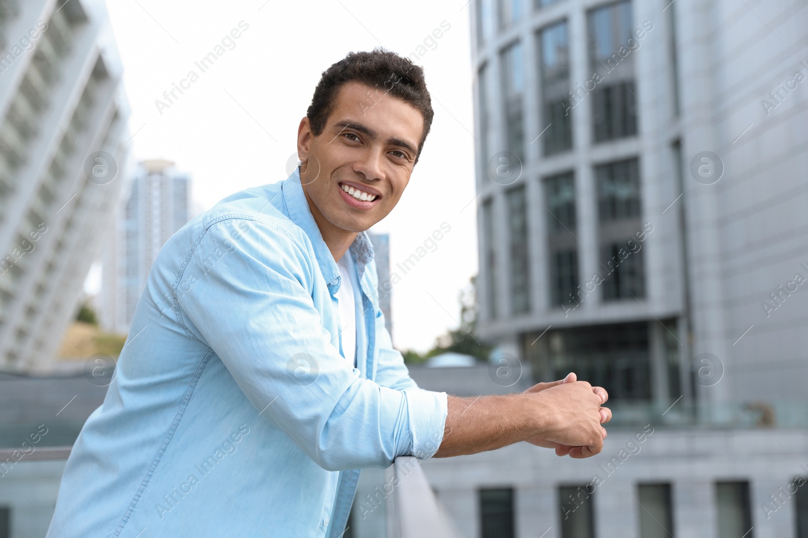 Photo of Portrait of handsome young African-American man on city street. Space for text