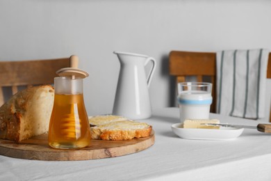 Photo of Delicious honey, milk and bread with butter served for breakfast on table