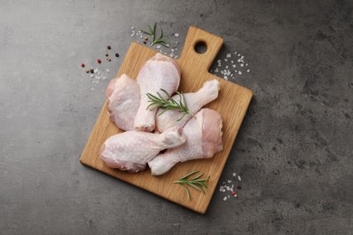 Raw chicken drumsticks with rosemary and spices on grey table, flat lay