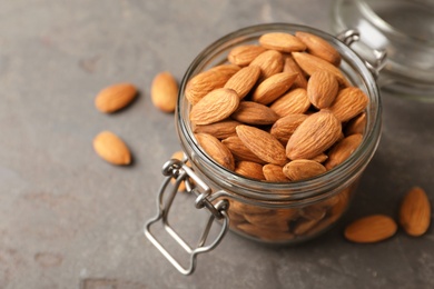Tasty organic almond nuts in glass jar on table. Space for text