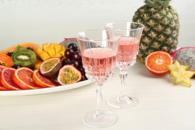 Photo of Delicious exotic fruits and wine on white wooden table