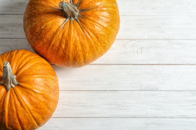 Orange pumpkins and space for text on light wooden background, top view. Autumn holidays