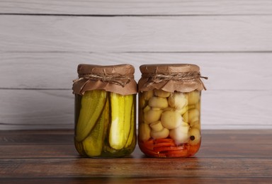 Photo of Jars with pickled vegetables on wooden table