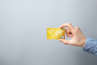 Photo of Young man holding credit card on grey background