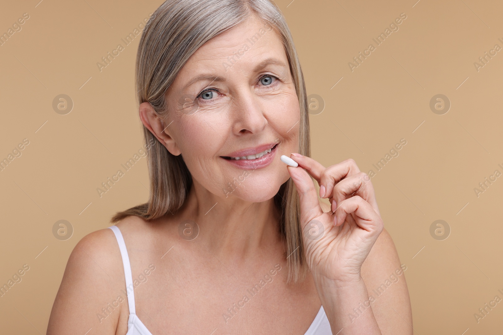 Photo of Beautiful woman with vitamin capsule on beige background