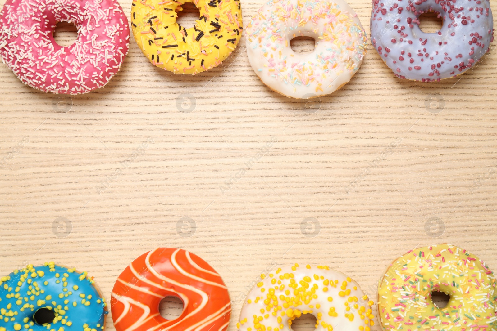 Photo of Delicious glazed donuts on wooden table, flat lay. Space for text