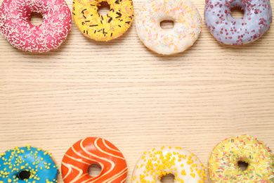 Delicious glazed donuts on wooden table, flat lay. Space for text