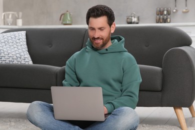 Man using laptop on floor at home