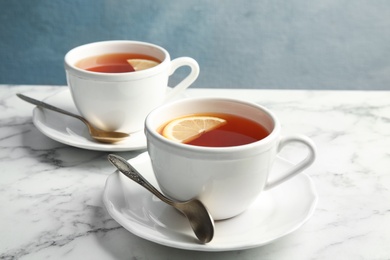 Photo of Cups with black tea and lemon on marble table