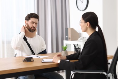 Photo of Injured man having meeting with lawyer in office, selective focus