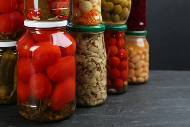 Photo of Jars of pickled vegetables on grey table, closeup