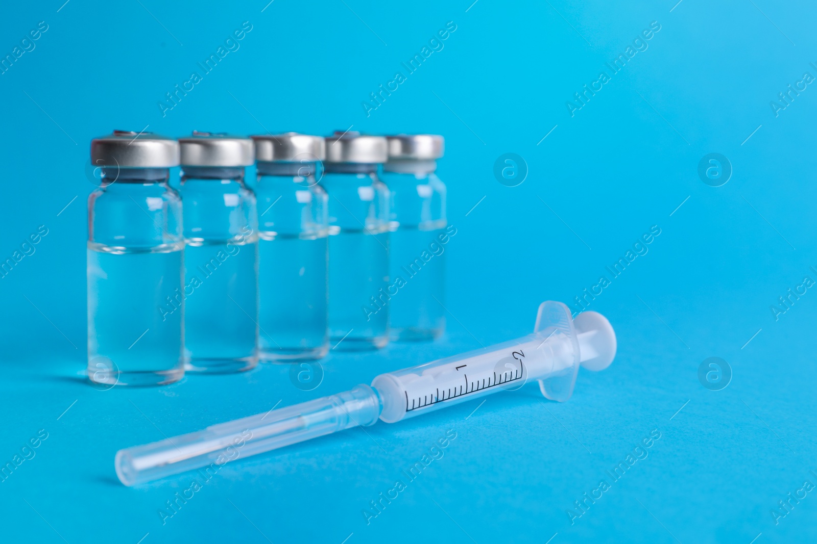 Photo of Disposable syringe with needle and vials on light blue background