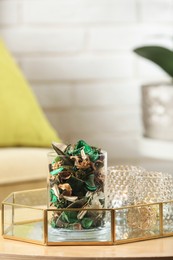 Photo of Glass jar with aromatic potpourri of dried flowers and different decor element on wooden table indoors