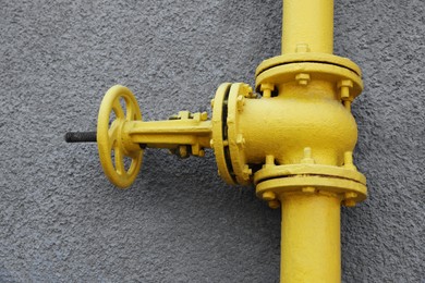 Yellow gas pipe on grey wall outdoors, closeup
